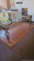Full view of coffee table showing glass top and metal frame with ornamental details.