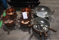 Four copper pots with side handles, one large hammered metal bowl with handles, smaller hammered bowl with copper rim containing four spoons with copper engraved handles.