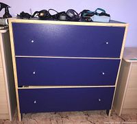 Front view of blue 3-drawer dresser showing all drawer fronts and knobs.