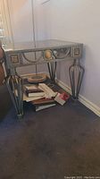 End table against wall with visible decorative metal legs and glass top, floor level items underneath