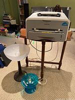 Samsung ML-1710 laser printer positioned on wooden table with two plastic lamps placed beside the table on the floor.