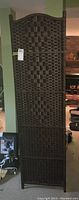 Single closeup panel showing rectangular woven pattern with arched top, dark brown color, with a tag attached.