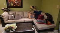 Full view of L-shaped sectional sofa with beige ultrasuede cushions and black faux leather base