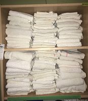 Two shelves filled with stacks of white folded towels, some towels have pink stripes along the edge.