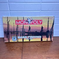 Front view of the sealed Bass Fishing Monopoly game box showing the lakeside sunset scene and game branding.
