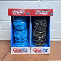 Front view of the Superman and Batman Justice League Geeki Tiki mugs in their original packaging, showing detailed tiki-style sculpting and colors.