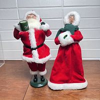 Full view of both Santa Claus and Mrs. Claus Byers Choice figures standing side by side showing outfits and bases.