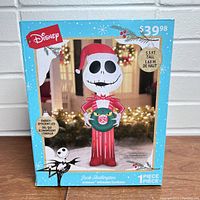Box front showing Jack Skellington inflatable figure with Santa hat holding wreath. Shows energy-efficient LED lighting and size 5.5 ft tall.