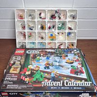 Photo showing Lego City 2017 Advent Calendar box and plastic tray with 24 unopened bags of Lego pieces organized in compartments.