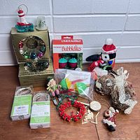 Mixed vintage Christmas decorations including boxed NOMA Bubblelites, glass reflector, Santa figurine, reindeer, wreath, and small ornaments arranged on floor