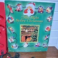 Front of the original green cardboard box showing the product name, light strand with character lights, and central Santa head light.