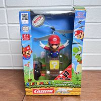 Front view of the boxed Nintendo Super Mario remote control helicopter showing Mario figure with rotors and colorful packaging.