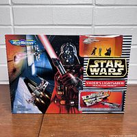 Box front showing box art featuring Darth Vader with lightsaber and Micro Machines branding, indicates the playset theme as Vader's Lightsaber/Death Star Trench