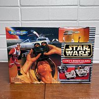 Front of the boxed Star Wars Micro Machines Luke's Binoculars Yavin Rebel Base set with artwork showing Luke holding binoculars and various playset scenes.