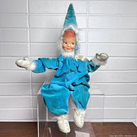 Front view of vintage Christmas elf doll sitting with arms open, showing turquoise velvet outfit and white fur trim.