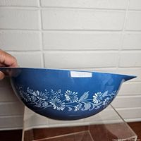 Side view of the blue mixing bowl showing white floral pattern on side.