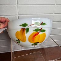 Side view of vintage Fire King fruit bowl showing yellow peaches and leaves painted on white glass.