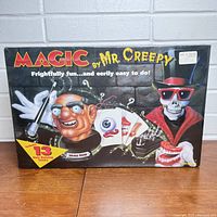Front view of sealed box with colorful creepy skeleton and head artwork, showing the set title and highlights including 13 hair raising tricks.