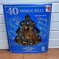 Original blue cardboard packaging labeled '40 MUSICAL BELLS', showing musical notes and bells behind tree-shaped window. Price sticker on top right corner.