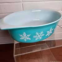 Front angle view of the vintage PYREX dish showing the turquoise exterior with white snowflake pattern and light blue interior.