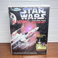 Front view of sealed Star Wars X-Wing Estes rocket starter set box showing product graphics and logos.