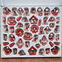 Top-down view of all 49 vintage wooden Christmas ornaments neatly arranged in white plastic tray inside the original box.