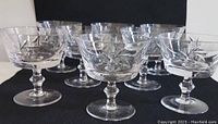 Front angle view of 10 vintage hand cut crystal dessert cups arranged in rows showing details of cut designs on bowls and stems.