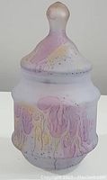 Front view of the white hand painted vanity jar with purple and yellow accents, showing the lid with knob handle and rounded jar body.