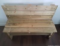 Top view of wooden bench showing plank seat and backrest with visible wood knots and grain.