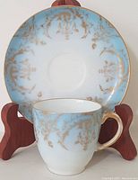 Front view of antique Limoges demitasse cup and matching saucer on wooden stand