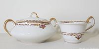 Front view of Limoges Chamberry creamer and sugar bowl showing white porcelain with floral garlands and gold trim detail
