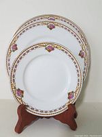 Three plates displayed: large dinner plate, medium salad plate, smaller side plate. Plates show decorative gold and floral pattern borders.