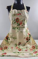 Full front view of the handcrafted vintage apron showing floral print, front pocket, and buttoned straps.