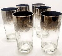 Front view of 6 highball glasses arranged in two rows showing silver fade embossed floral pattern around the top rim.