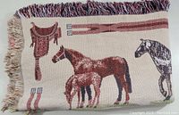 Folded Goodwin Weavers throw blanket showing horse designs, fringed edges at one side
