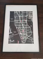 Framed New York City map print showing Manhattan with surrounding rivers and boroughs.