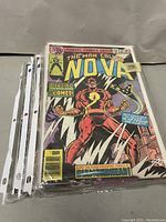 Stack of comic books in plastic sleeves with an example cover of "The Man Called Nova" Marvel comic
