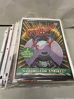 Stack of comic books in plastic sleeves showing Amazing Spider-Man issue with 'The Chameleon Strikes!' cover