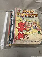 Stack of assorted comic books in plastic sleeves with an issue of Hot Stuff, The Little Devil visible on top