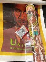 Malcolm X poster in yellow background with phrase 'By Any Means Necessary,' small box of history cards, rolled vintage-style poster.