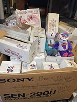 Large box filled with multiple bear boxes labeled as collectible bears from America's Value Showcase, with visible product boxes and some loose bears.