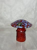 Side angle of red and purple spotted glass mushroom with Golden Crown E & R Sweden label on cap.