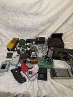 Wide shot showing diverse assortment of vintage cameras and phones on fabric backdrop