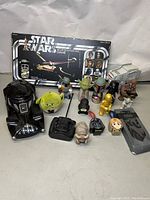 Display of Star Wars collectibles including boxed game, character figurines, plush, and helmet.