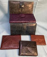 Full lot view showing six genuine leather wallets in assorted colors and embossed patterns