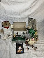 Full view of all lot items arranged on white patterned fabric background including plush bear golfer, boxed banks, brass trophies, and small golfer figurines.