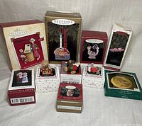 Overview of all 10 Hallmark Keepsake collectible Christmas ornaments arranged on a fabric surface, with most items in their original boxes.