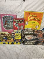 Photo of vintage kids games and activities including Fairy Tale Puzzles, Donkey Party, Junior Arithmetic game, Activity Box, and Electronic Detective game.