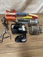 Vintage office supplies on a wooden surface including staplers, pencil sharpeners, staple boxes, and a manual wall-mounted sharpener