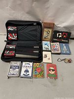 Vintage playing card decks of various brands lined at front with black poker set case holding chips and cards at back, dice on right